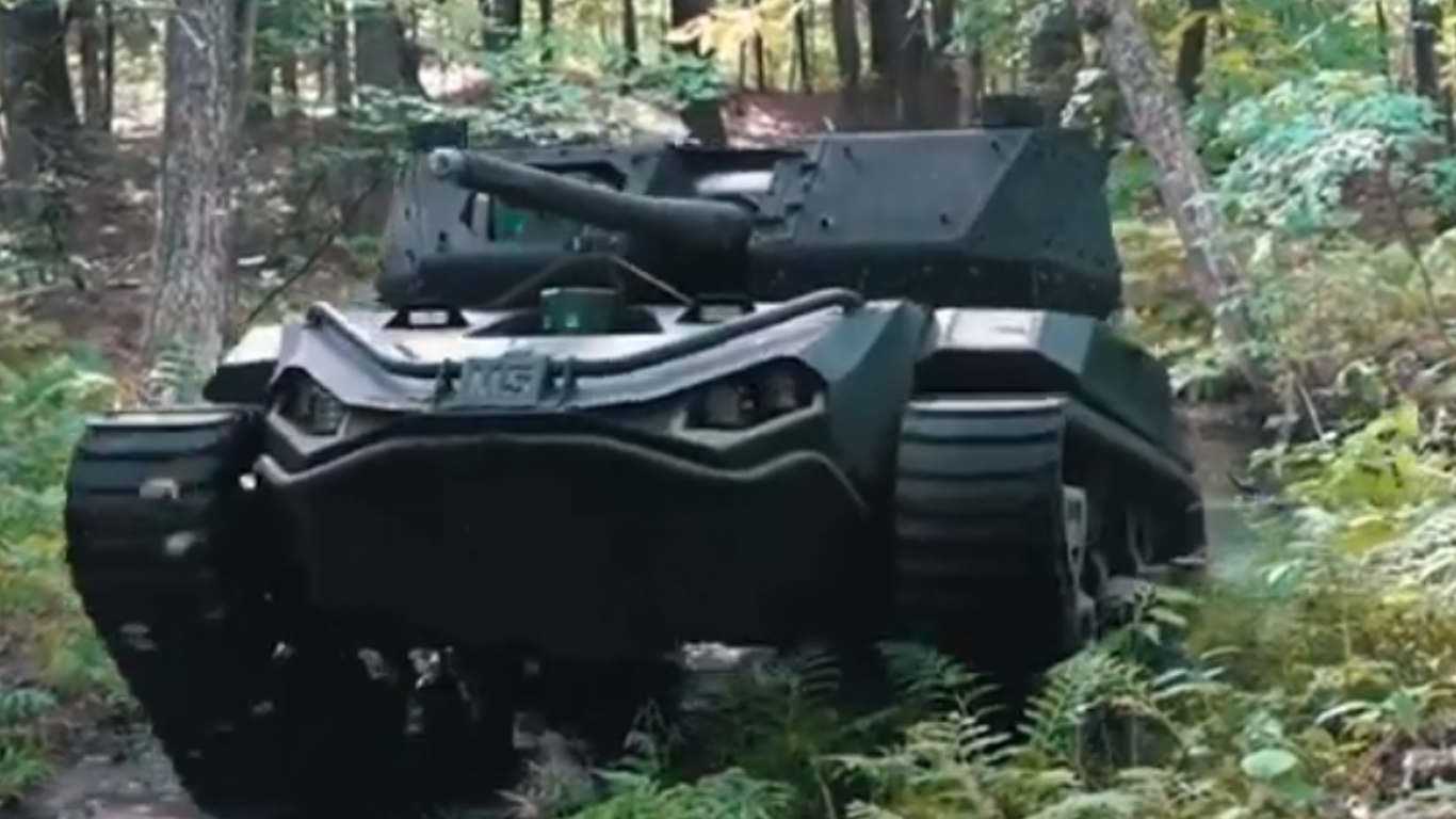 An unmanned tracked military vehicle with a mounted weapon system moving through a dense forest terrain, designed for autonomous combat or support missions.