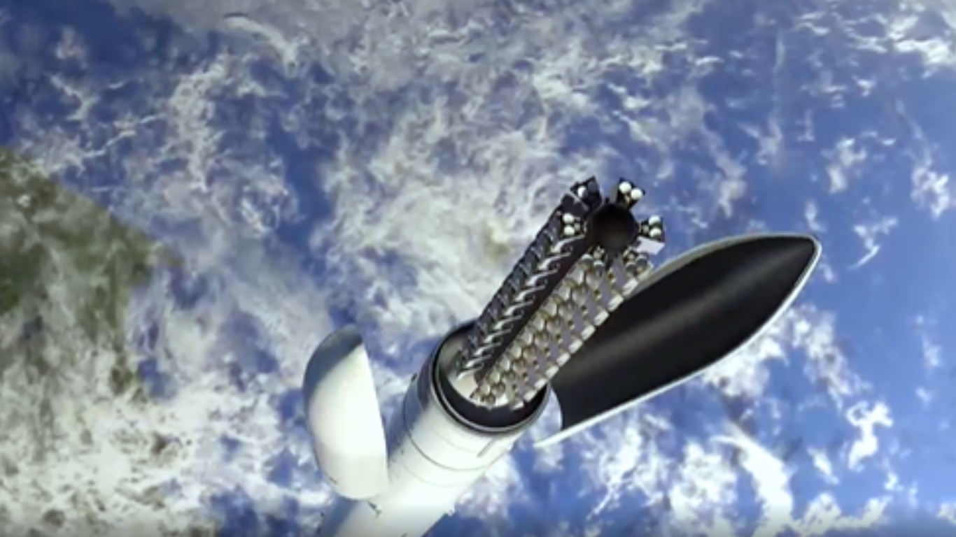 Satellite deployment system opening in orbit above Earth, releasing multiple small payloads or components.
