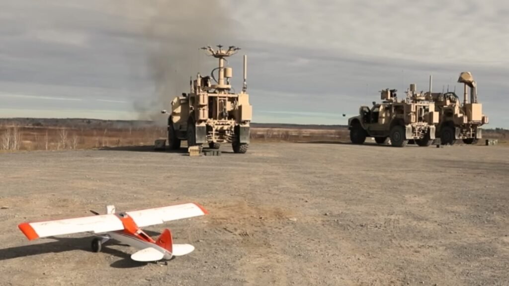 Military vehicles with electronic warfare antennas parked on a gravel field near a small drone, demonstrating Advanced Counter UAS Technologies.