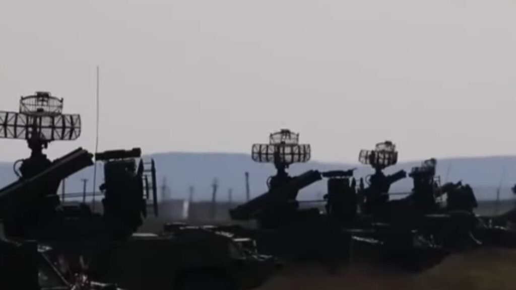 A row of mobile surface-to-air missile systems with rotating radar dishes, integrated into a unified AI combat cloud network.
