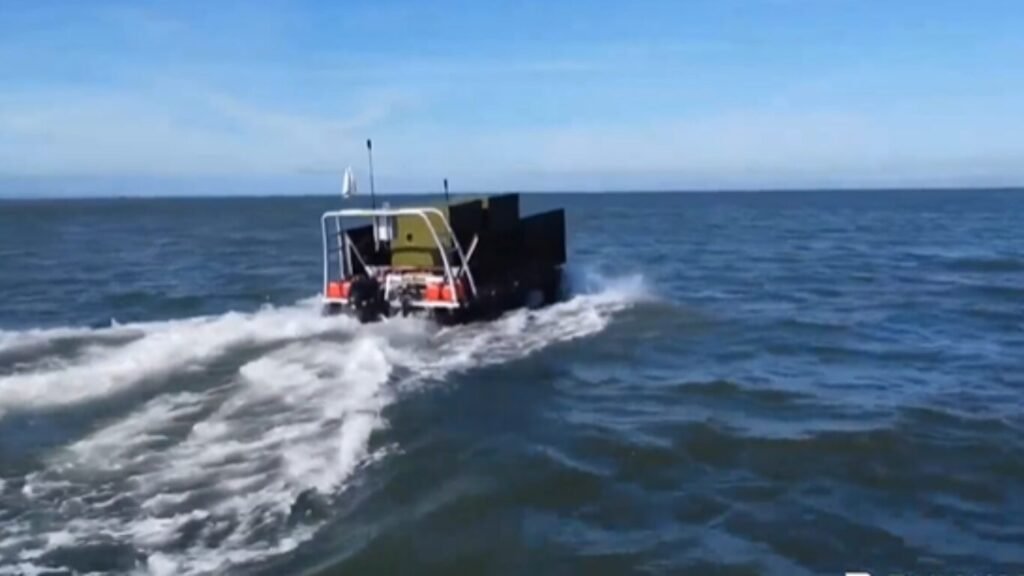 An unmanned amphibious cargo craft speeding across open water while carrying supplies, showcasing maritime solutions for AI Last Mile Resupply.