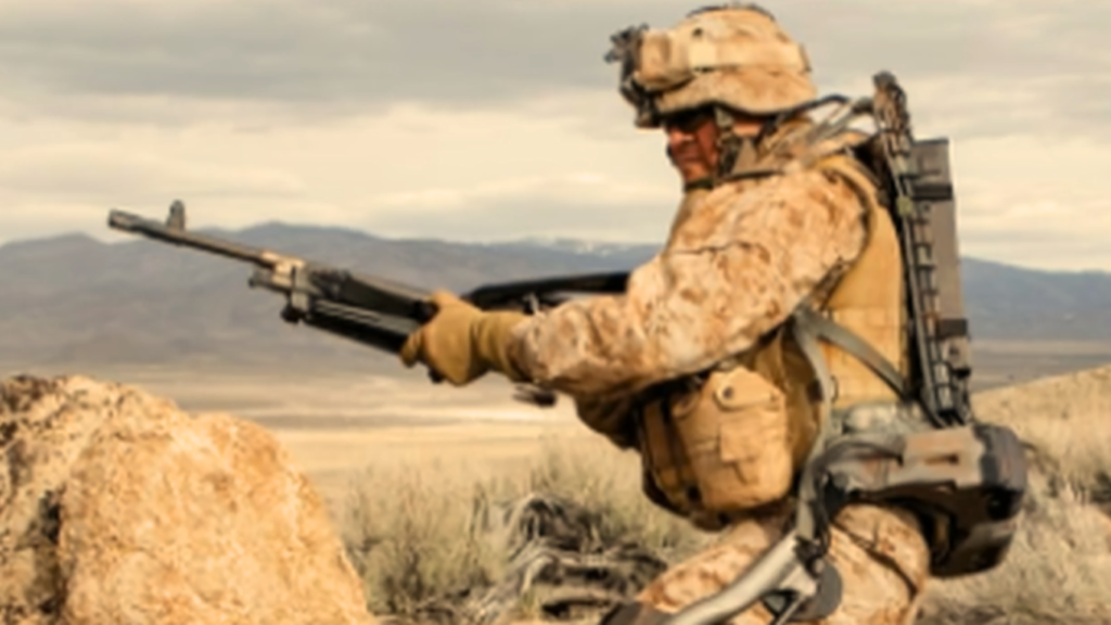 A soldier in desert camouflage gear utilizing AI Powered Exoskeletons while holding a rifle during a field training exercise in an arid, mountainous landscape.