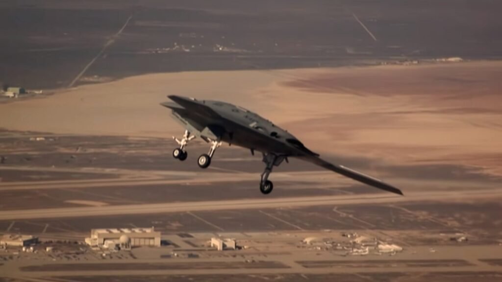 An X-47B stealth drone flying with its landing gear deployed over an airfield, showcasing advanced unmanned platforms utilized in AI Warfare.