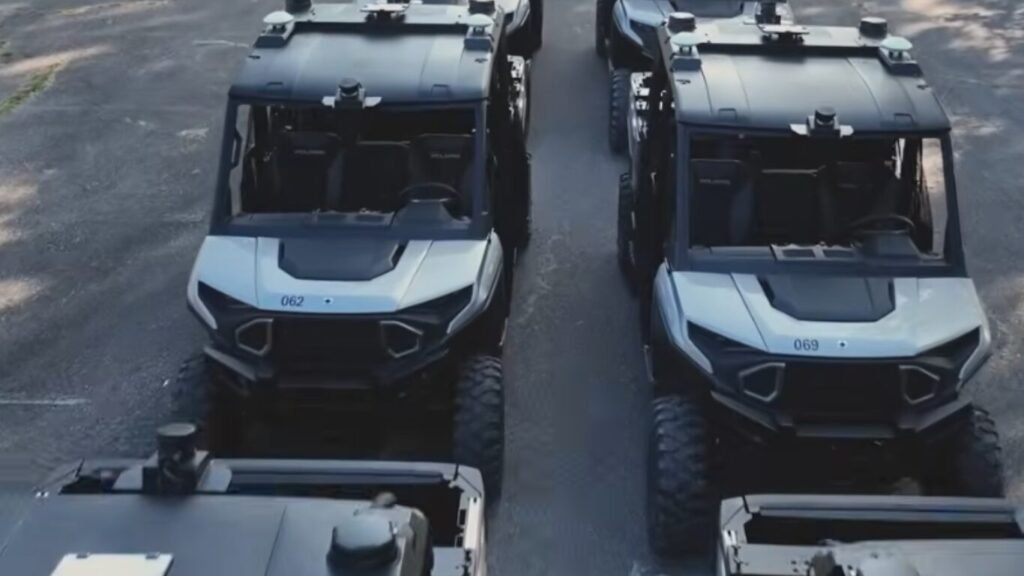 A fleet of silver and black UTVs equipped with roof-mounted sensors parked in formation, showcasing autonomous logistics in military operations.