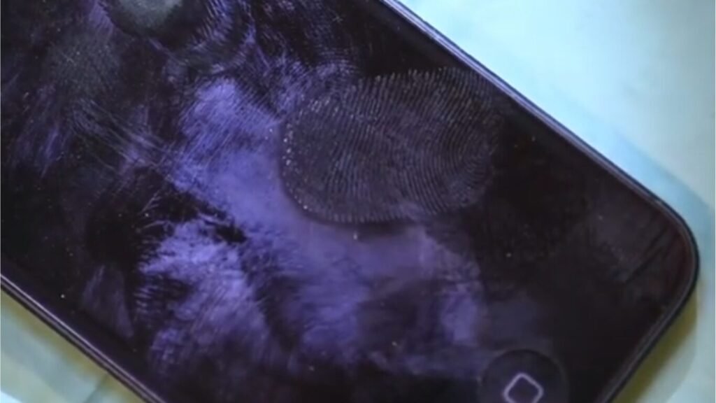 A close-up of a dark smartphone screen showing oily smudge marks and a clear, detailed fingerprint pattern, highlighting concepts of Biometric IFF.