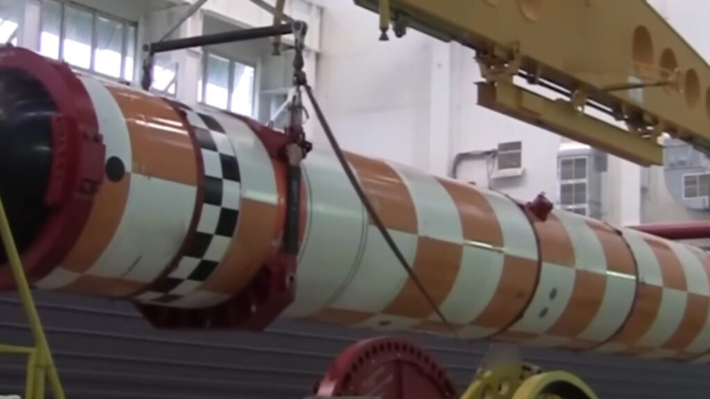 A massive orange and white checkered autonomous underwater vehicle suspended by a crane hoist inside a facility, highlighting structural hardware that prompts global debate over the Ethics of Lethal Autonomous Weapons.