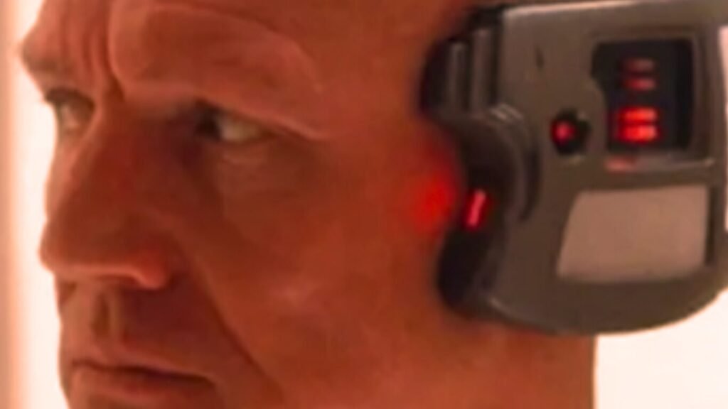 A close-up of a man with a cybernetic head implant featuring glowing red lights, illustrating how Neural Link Squad Coordination is changing the way military teams work.