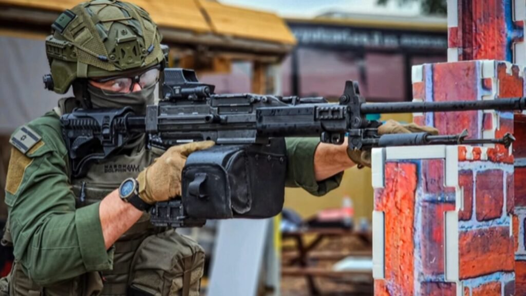 A soldier aiming a machine gun equipped with an advanced optic system designed for predictive ballistics tracking.