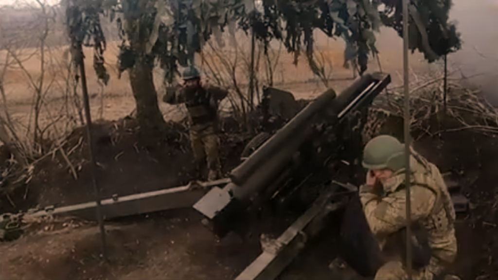 Two soldiers operating an artillery piece in a camouflaged trench, exemplifying tactical field integrations linked to Project Replicator.