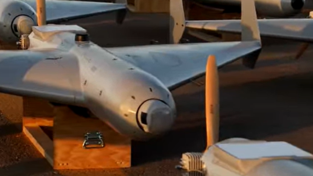 A row of gray delta-wing loitering munitions resting on wooden crates on an asphalt tarmac, demonstrating mass-producible autonomous systems aligned with Project Replicator.