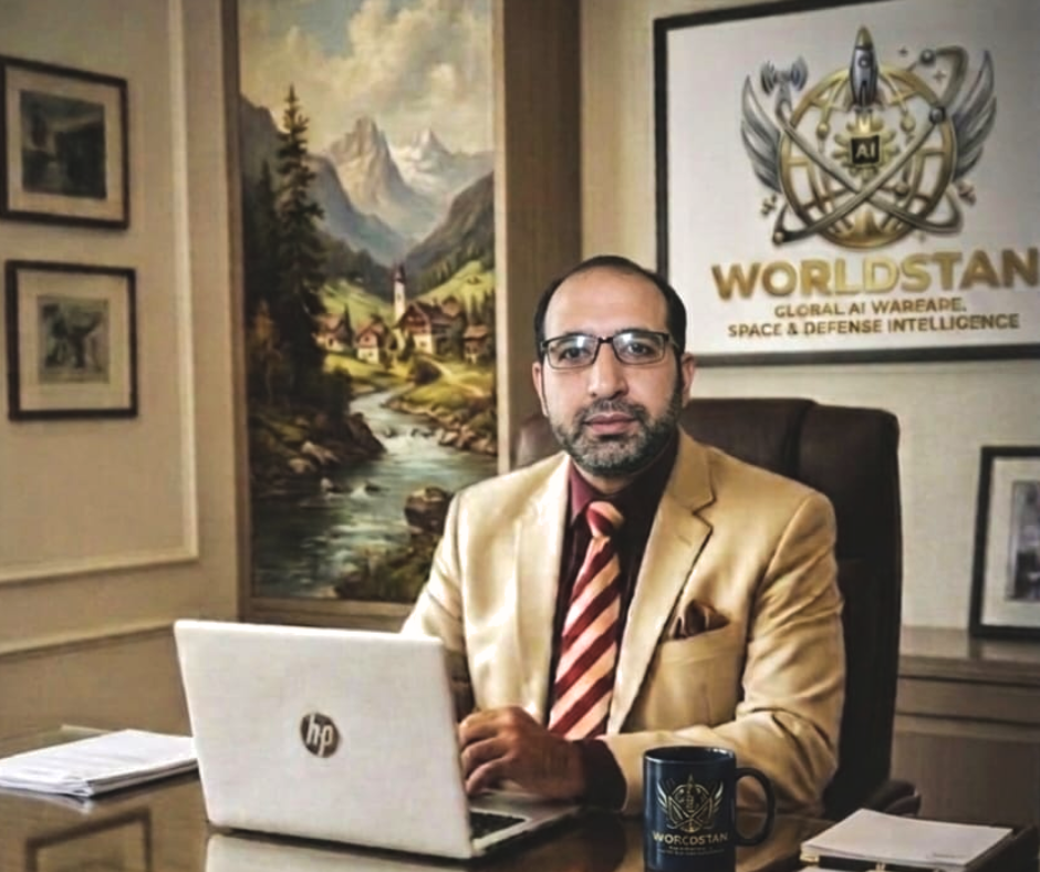 Professional office portrait for the ABOUT US WAQAR FOUNDER OF WORLDSTAN section, showing Waqar seated at a desk with an HP laptop and a branded Worldstan mug in front of corporate signage.