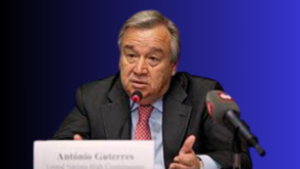 António Guterres, Secretary-General of the UN, speaking at a press conference microphone, illustrating a climate address where the United Nations announced AI Methane Detection frameworks. He wears a dark business suit and a pattern-textured tie against a smooth royal blue background.