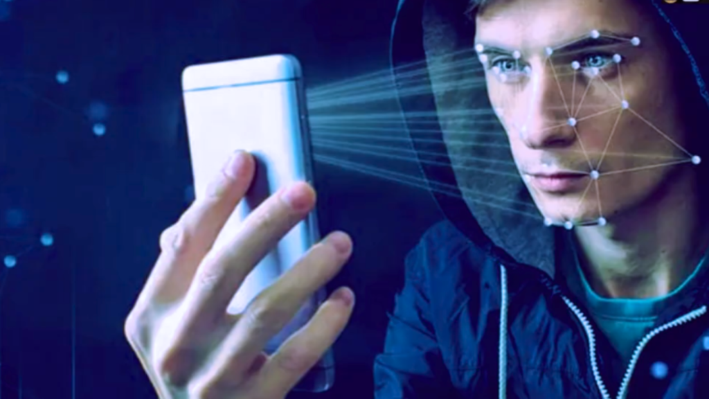 Close-up of a person in a hoodie holding a smartphone that emits light rays to map facial data points, demonstrating Edge AI Optimization for biometrics.