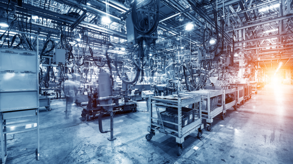 An automated industrial factory floor with assembly line machinery and overhead cables, illustrating where Edge AI Hardware for Enterprise Applications is deployed to optimize manufacturing processes in real time.