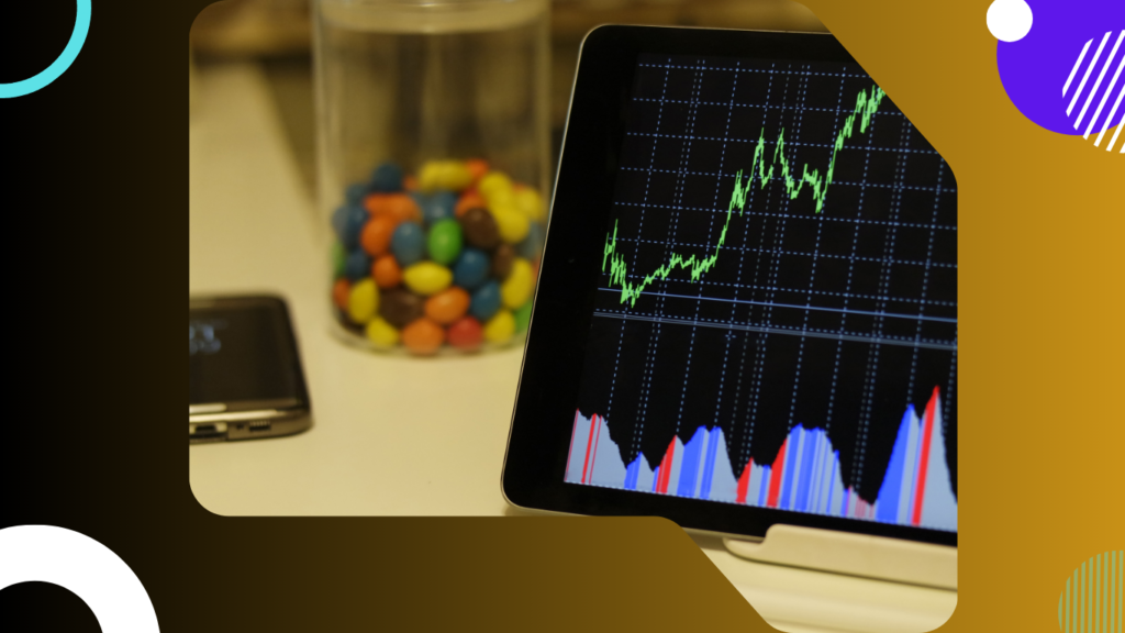 A digital screen displaying a green upward-trending line chart and multi-colored data bars on a black grid background, representing predictive AI analytics models processing retail market shifts, positioned on a desk next to a blurred smartphone and a glass jar filled with colorful candies.